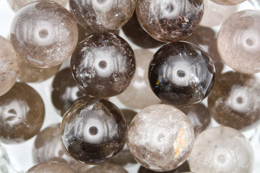 A collection of polished smoky quartz spheres of varying shades of brown and transparent edges.