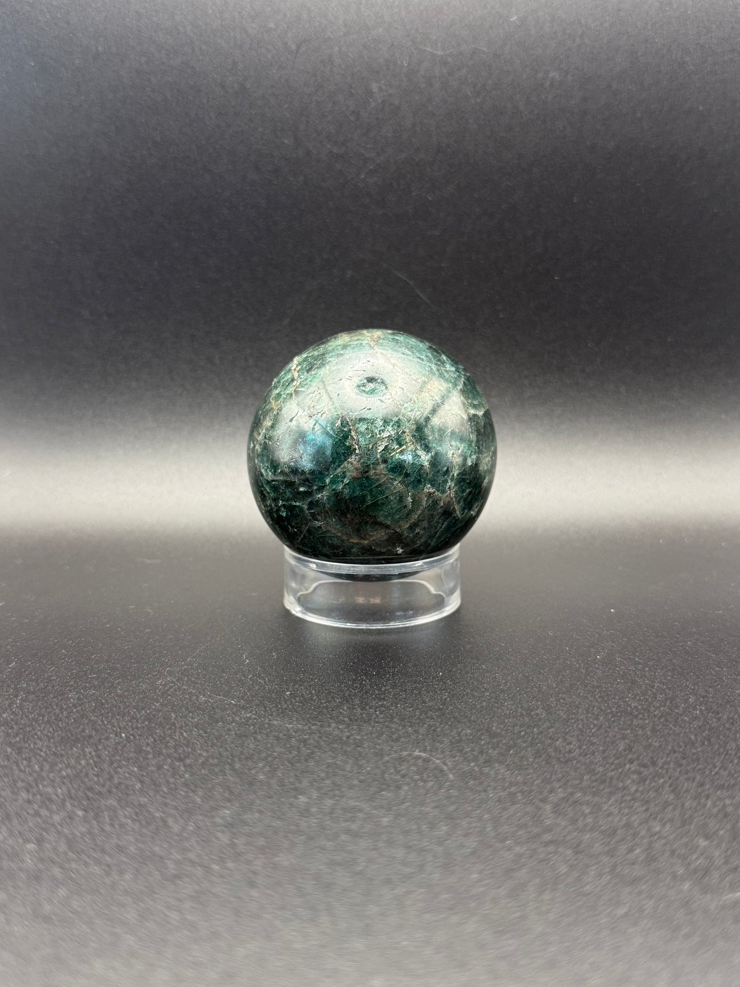 Polished green apatite crystal in the shape of a sphere.