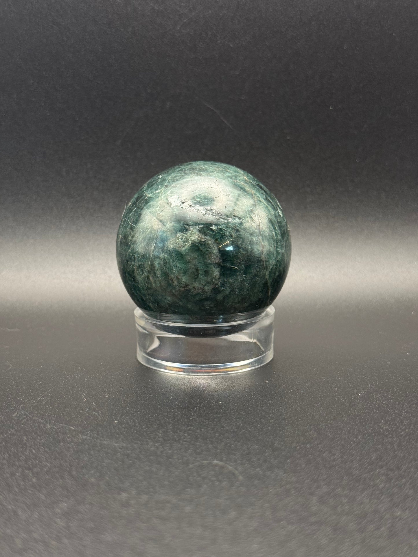 Polished green apatite crystal in the shape of a sphere.