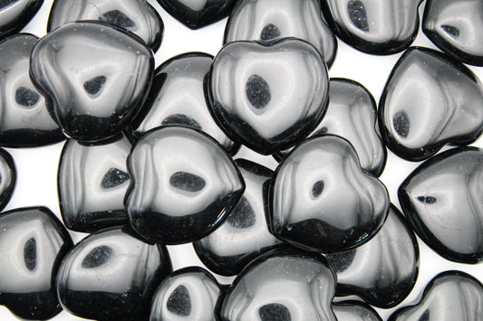 A collection of polished black obsidian hearts