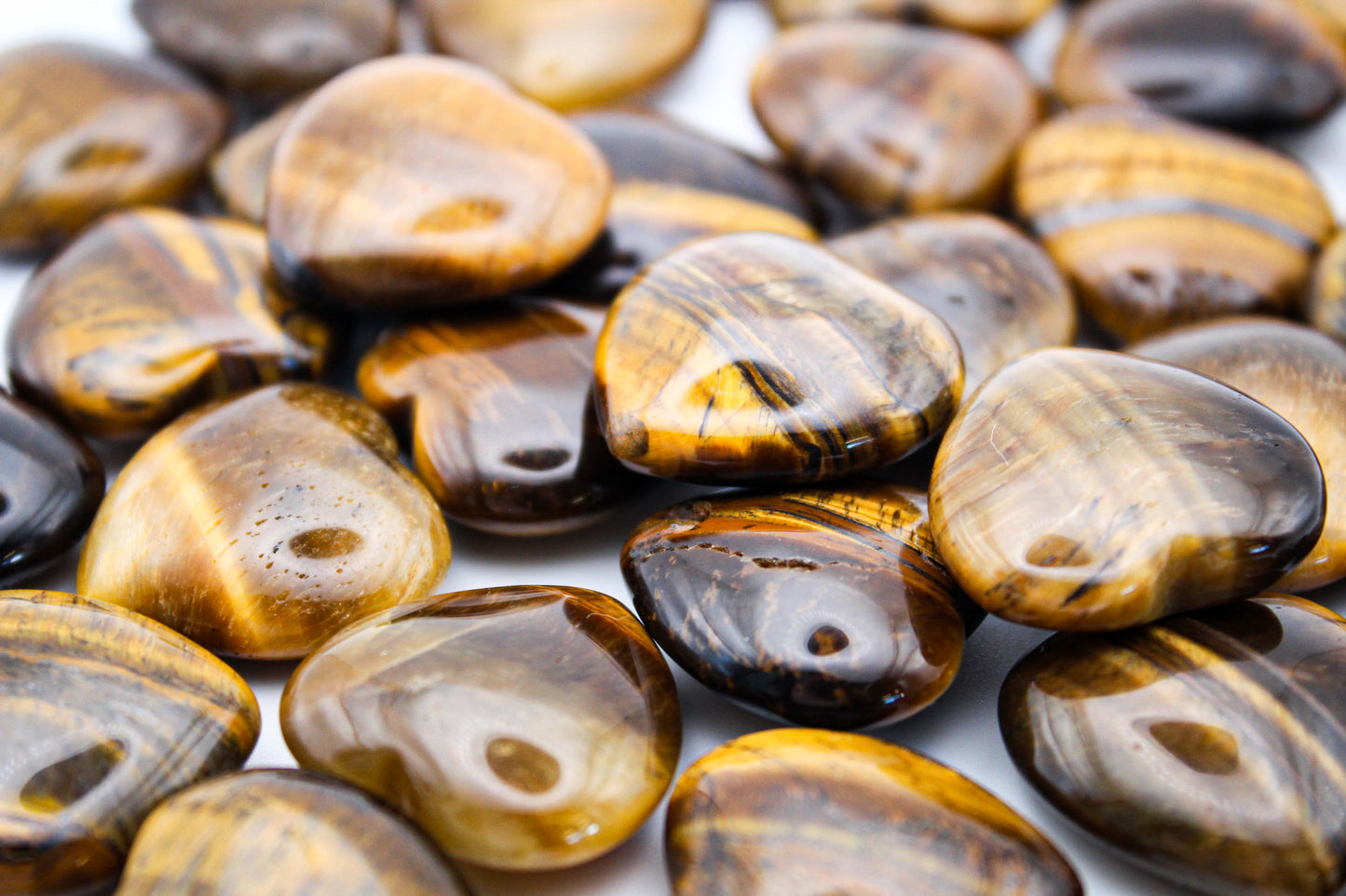 A collection of polished yellow tiger eye hearts with varying patterns.