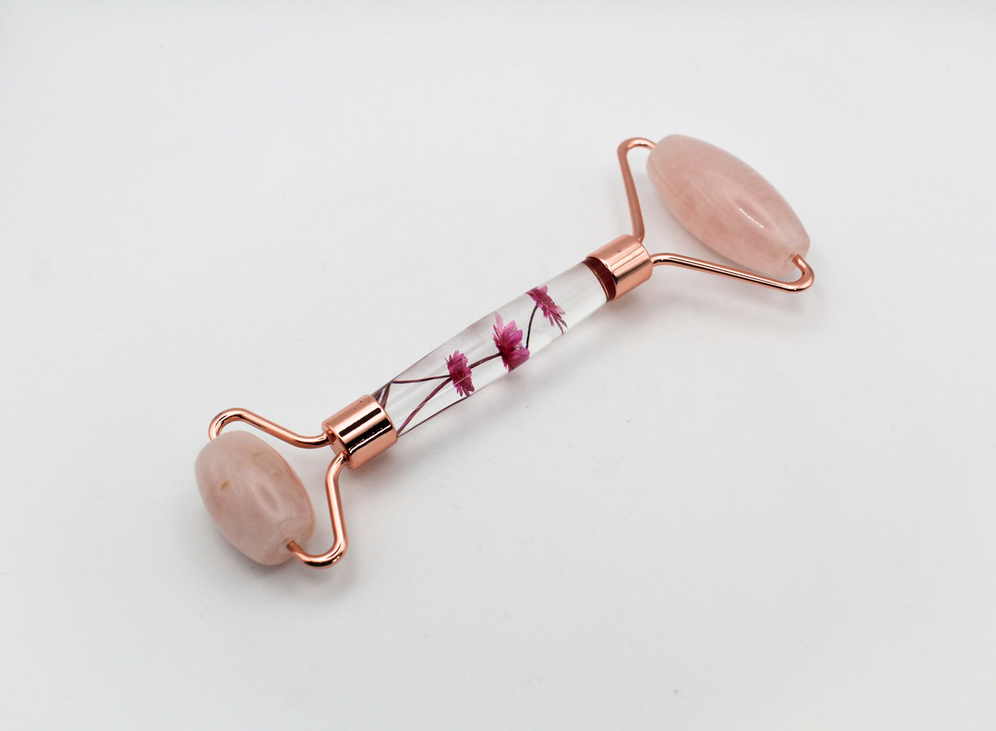 Massage roller with rose quartz rollers and pink flowers in the middle.