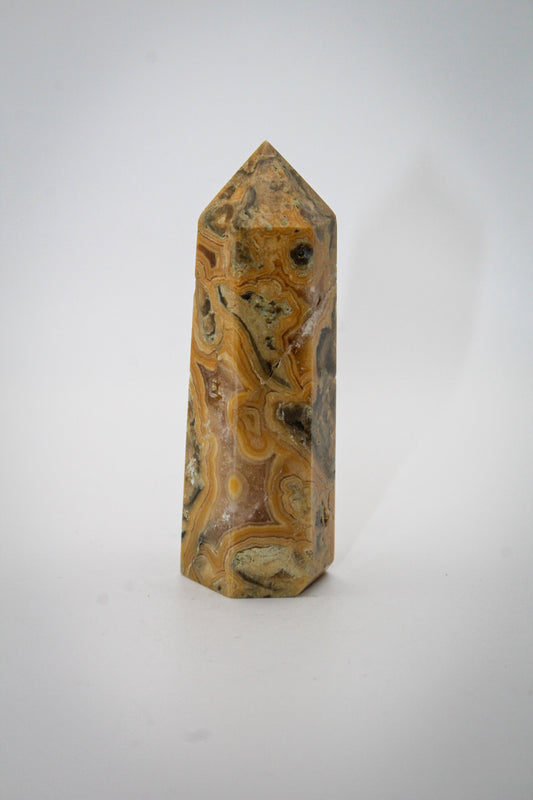 A polished yellow crazy lace agate crystal tower with natural variations in color and pattern.