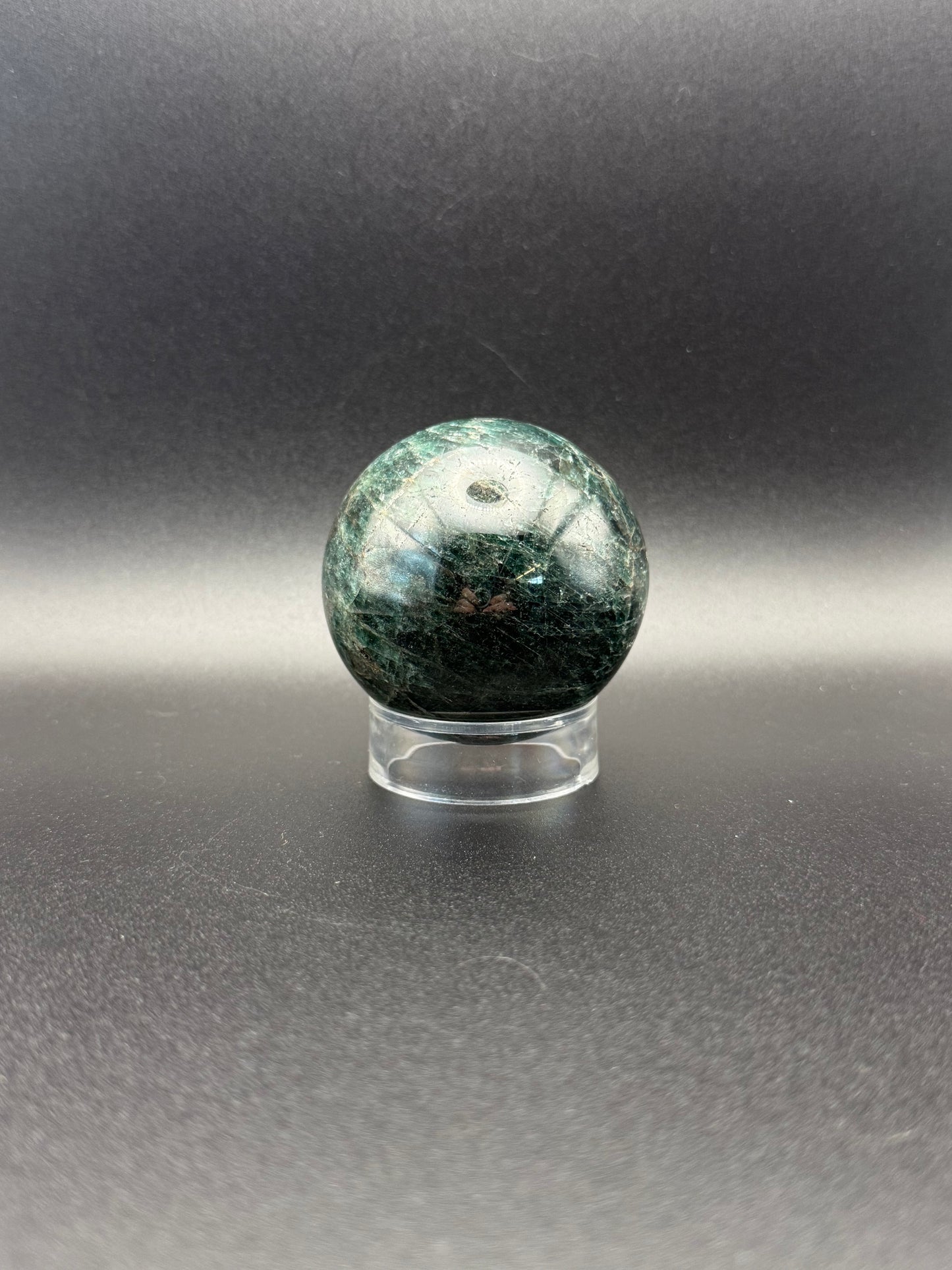 Polished green apatite crystal in the shape of a sphere.