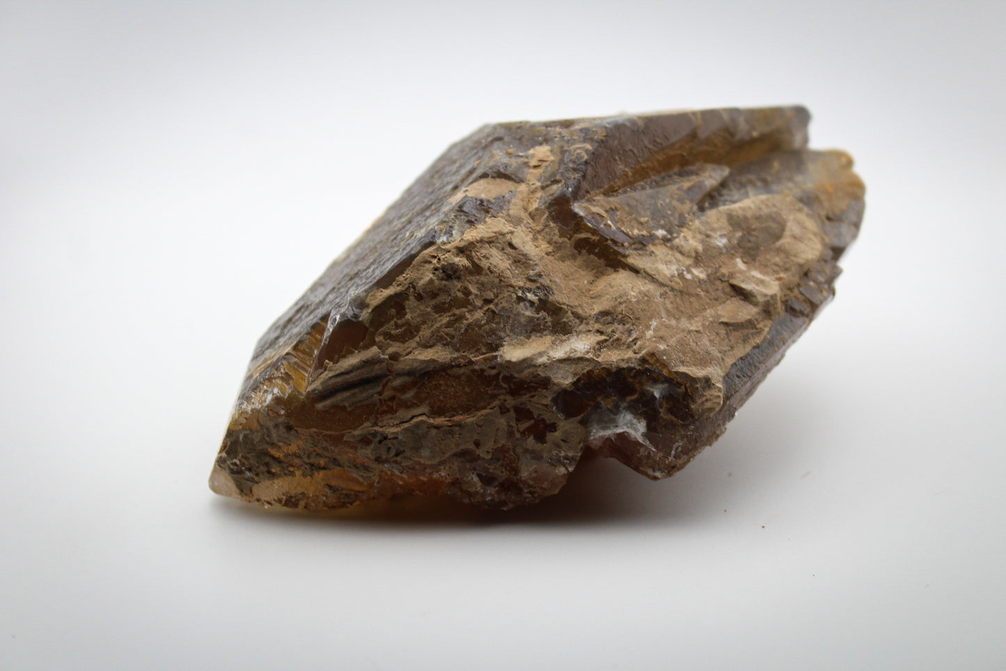 An elongated Dog Tooth Calcite crystal on a white background