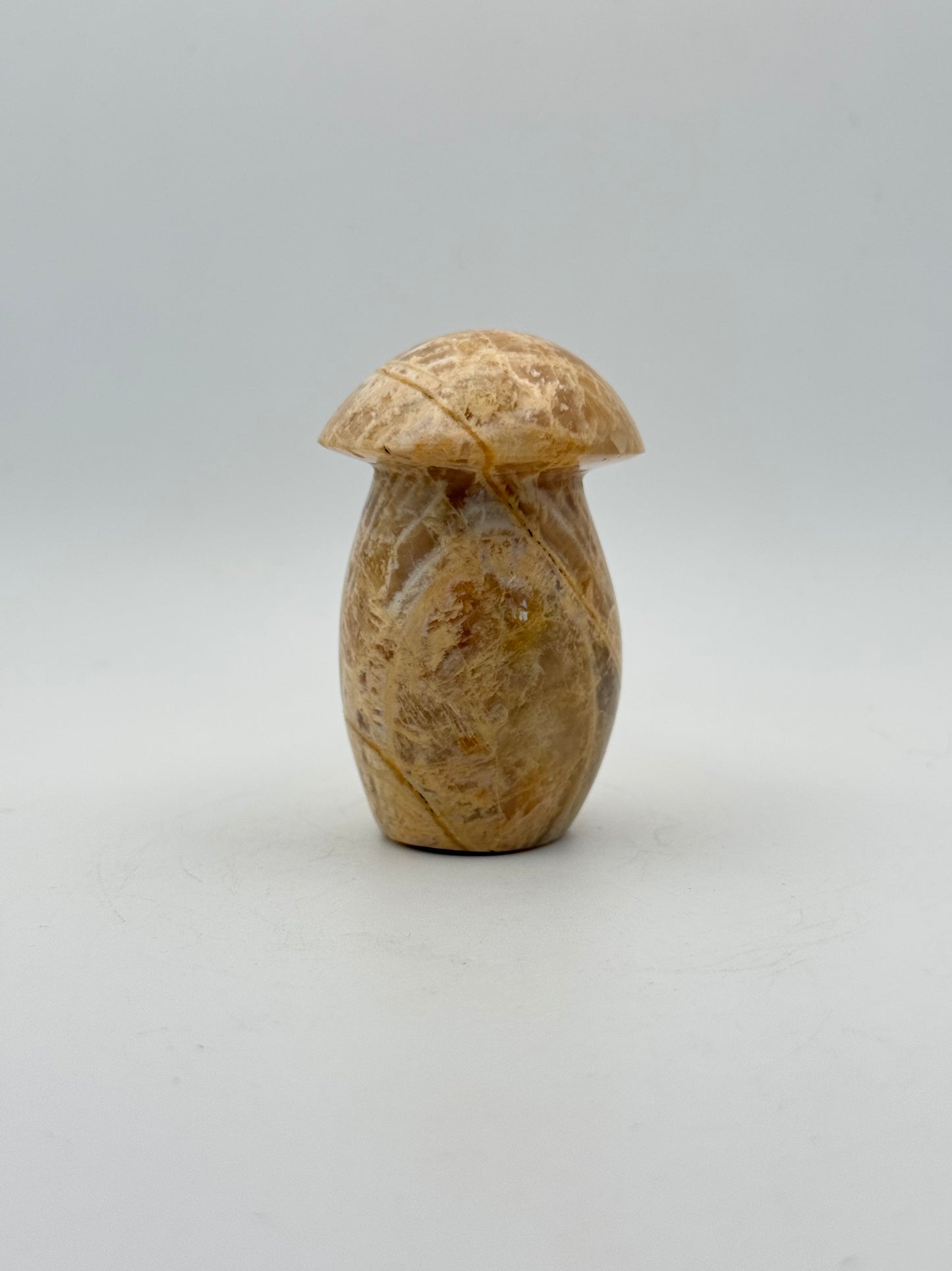 Polished yellow moonstone in the shape of a mushroom.