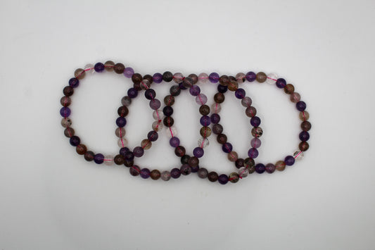 A series of multicolored beaded bracelets stacked together, featuring various shades of purple, brown, and clear.