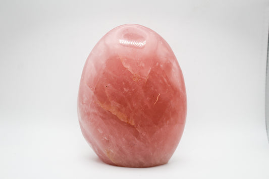 A polished, pink rose quartz crystal free form on a white background.