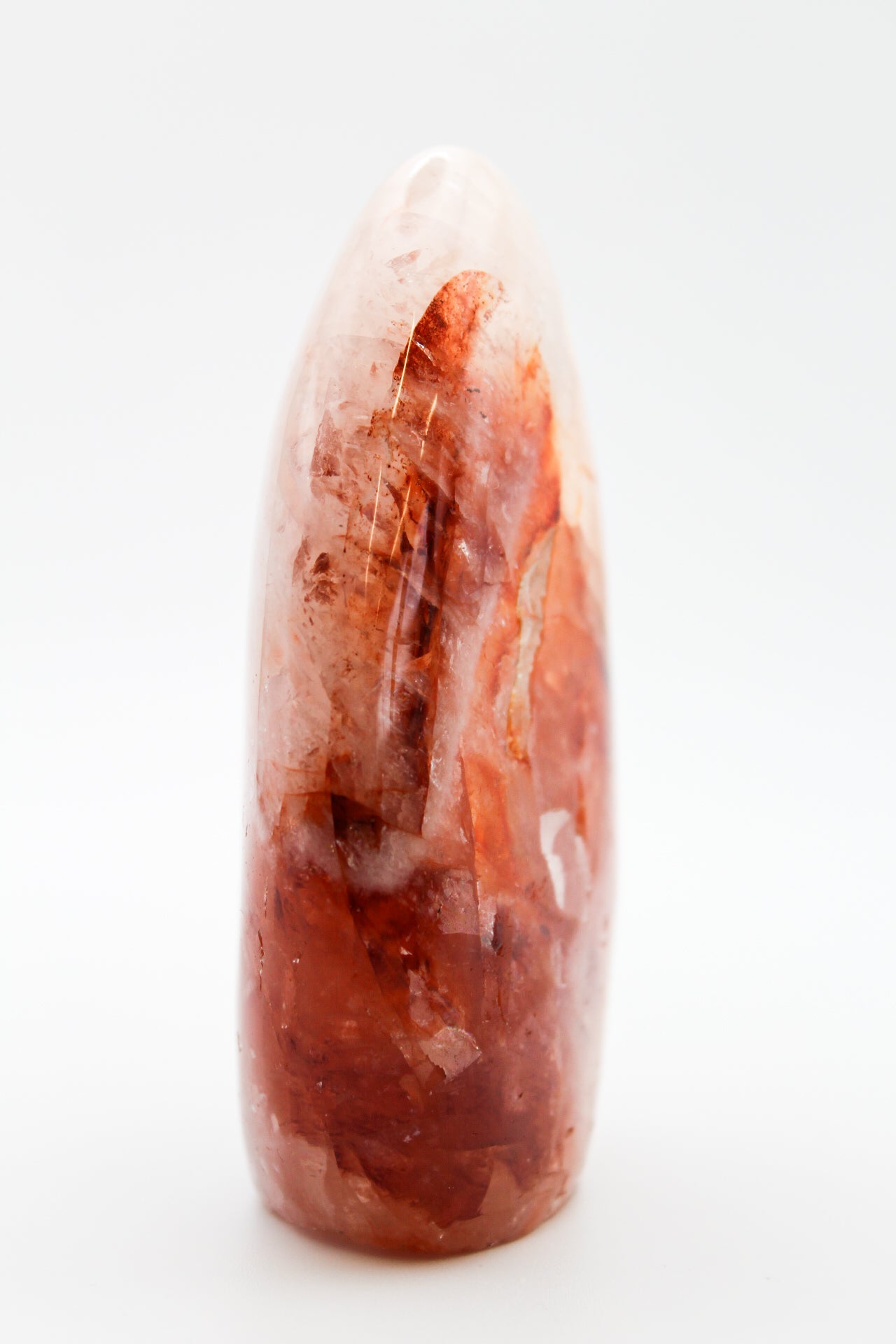 A polished red hematoid mineral free-form shape on a white background