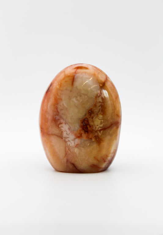 A polished carnelian stone with a free form shape, featuring an orange to red gradient color.