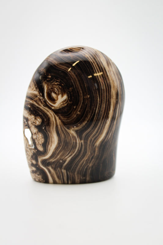 A polished chocolate calcite dome with a layered brown and white pattern, placed against a white background.