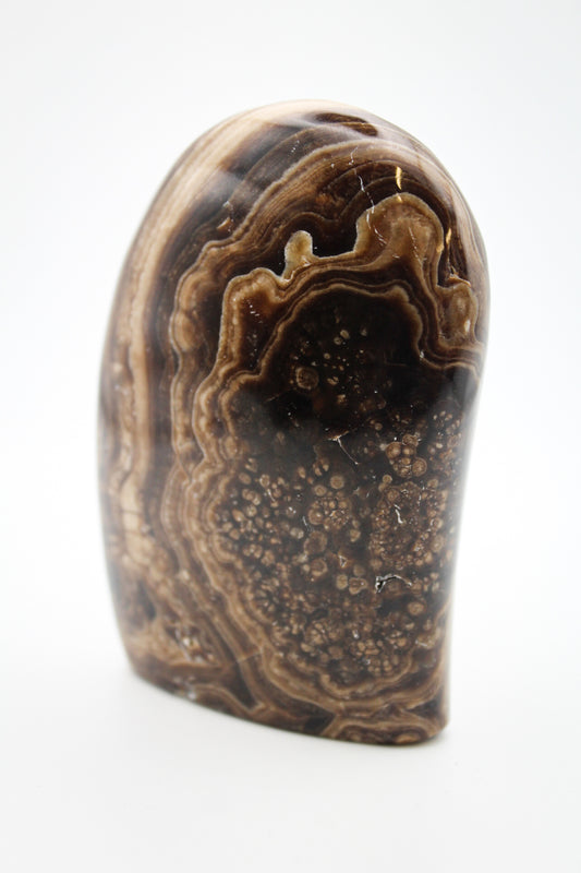 A polished chocolate calcite dome with a layered brown and white pattern, placed against a white background.