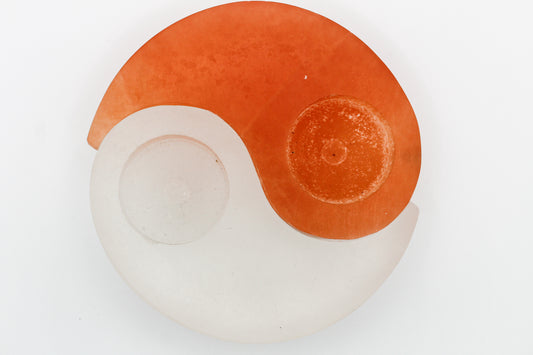 A selenite yin yang candle holder with a white and orange color scheme on a white background.