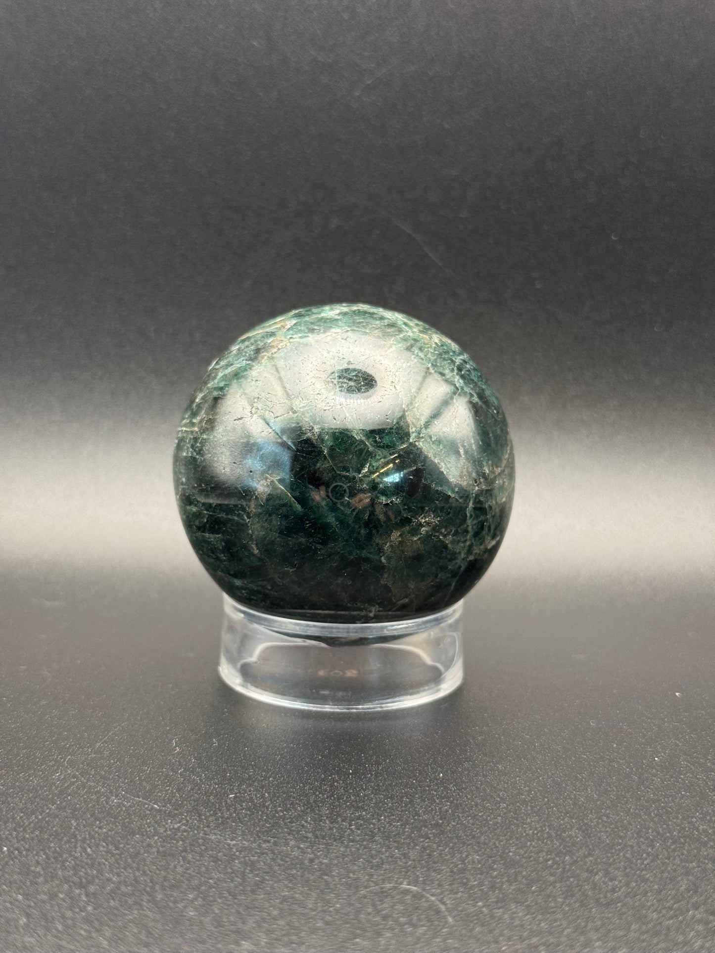 Polished green apatite crystal in the shape of a sphere.