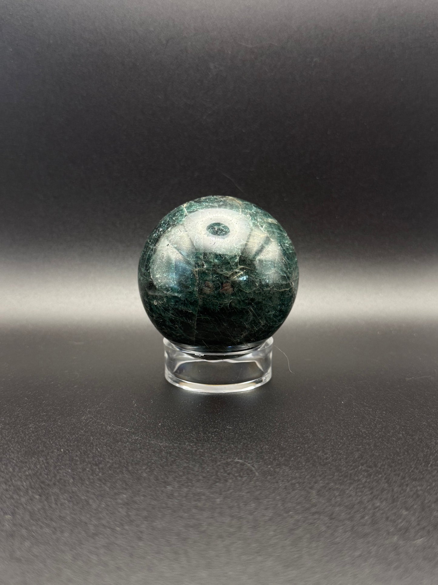 Polished green apatite crystal in the shape of a sphere.
