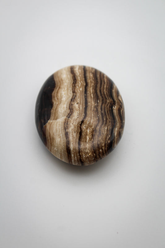 A polished chocolate calcite stone with a striped pattern, oval in shape.