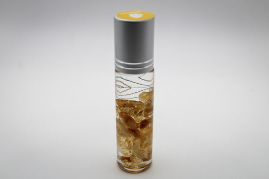 A clear glass roll-on bottle with a citrine sphere for application. The intention of this bottle is abundance. The scents are frankincense, geranium, and lavender.