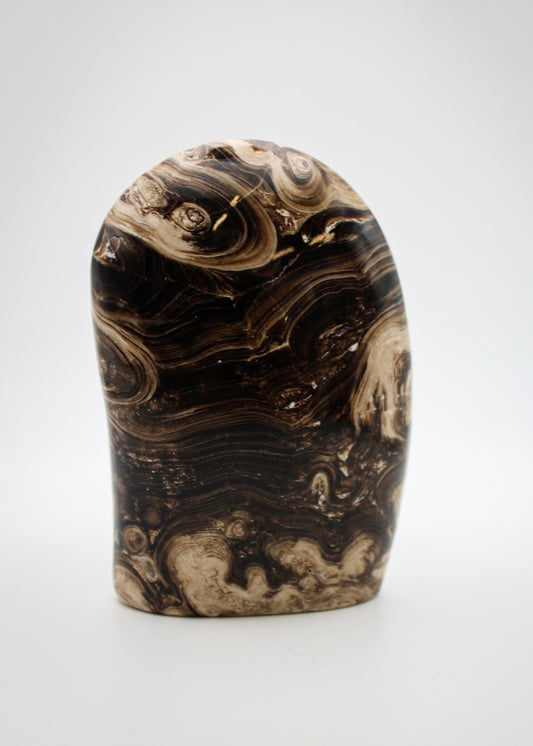 A polished chocolate calcite dome with a layered brown and white pattern, placed against a white background.