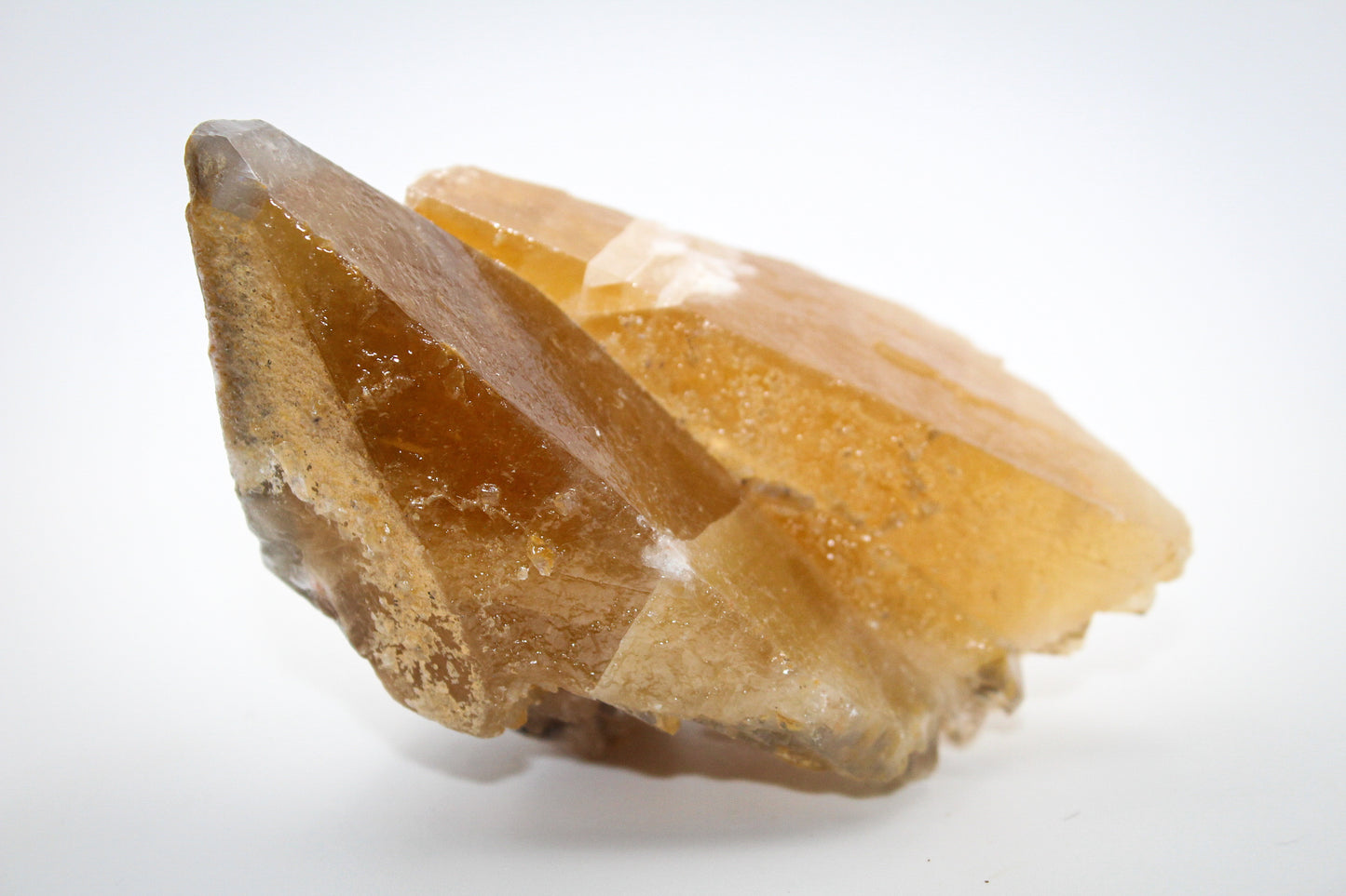 An elongated dog tooth calcite crystal with a golden hue.
