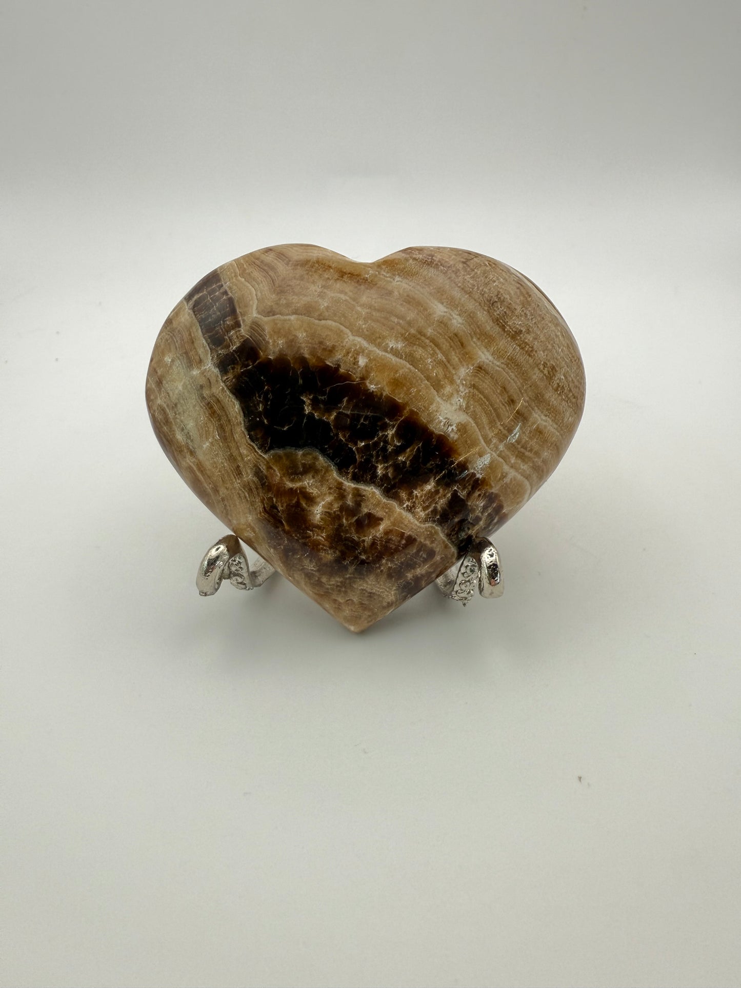 A polished chocolate calcite heart-shaped stone with a brown and white marbled pattern.