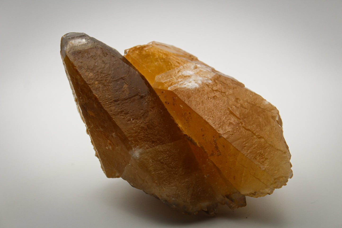An elongated dog tooth calcite crystal with a golden hue.