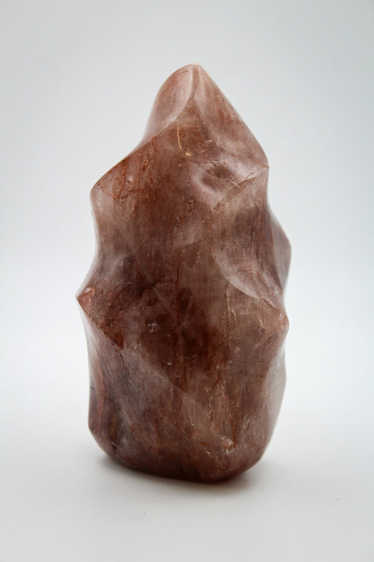 A red hematoid flame-shaped mineral specimen on a white background