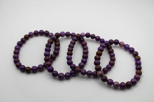 A series of round phosphosiderite beads with varying shades of purple and brown, arranged on a white background.
