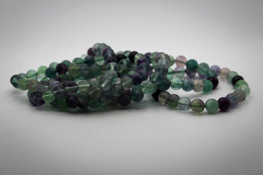 A bracelet made of round green fluorite beads laid out on a flat surface.