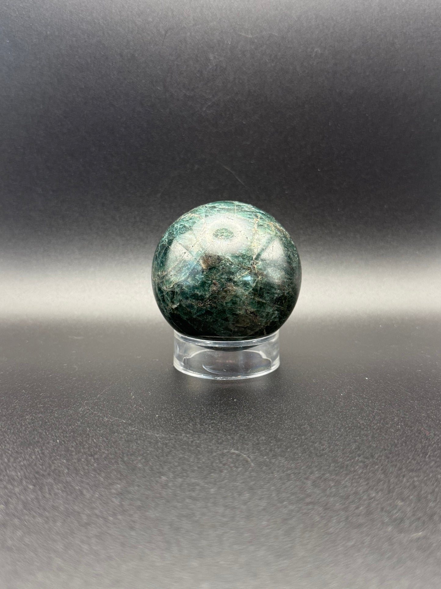 Polished green apatite crystal in the shape of a sphere.