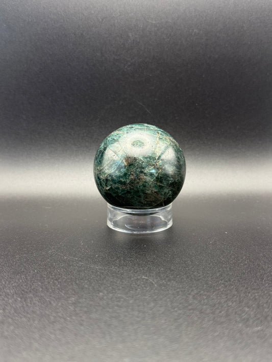 Polished green apatite crystal in the shape of a sphere.