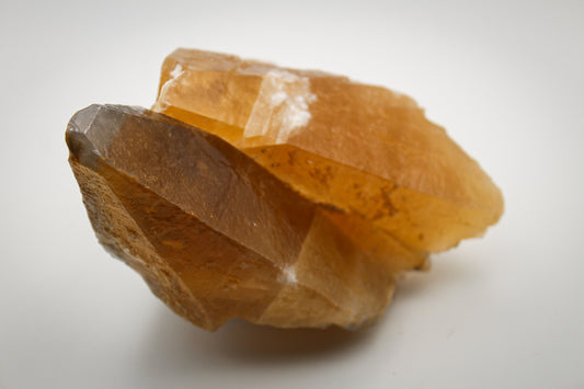 An elongated dog tooth calcite crystal with a golden hue.