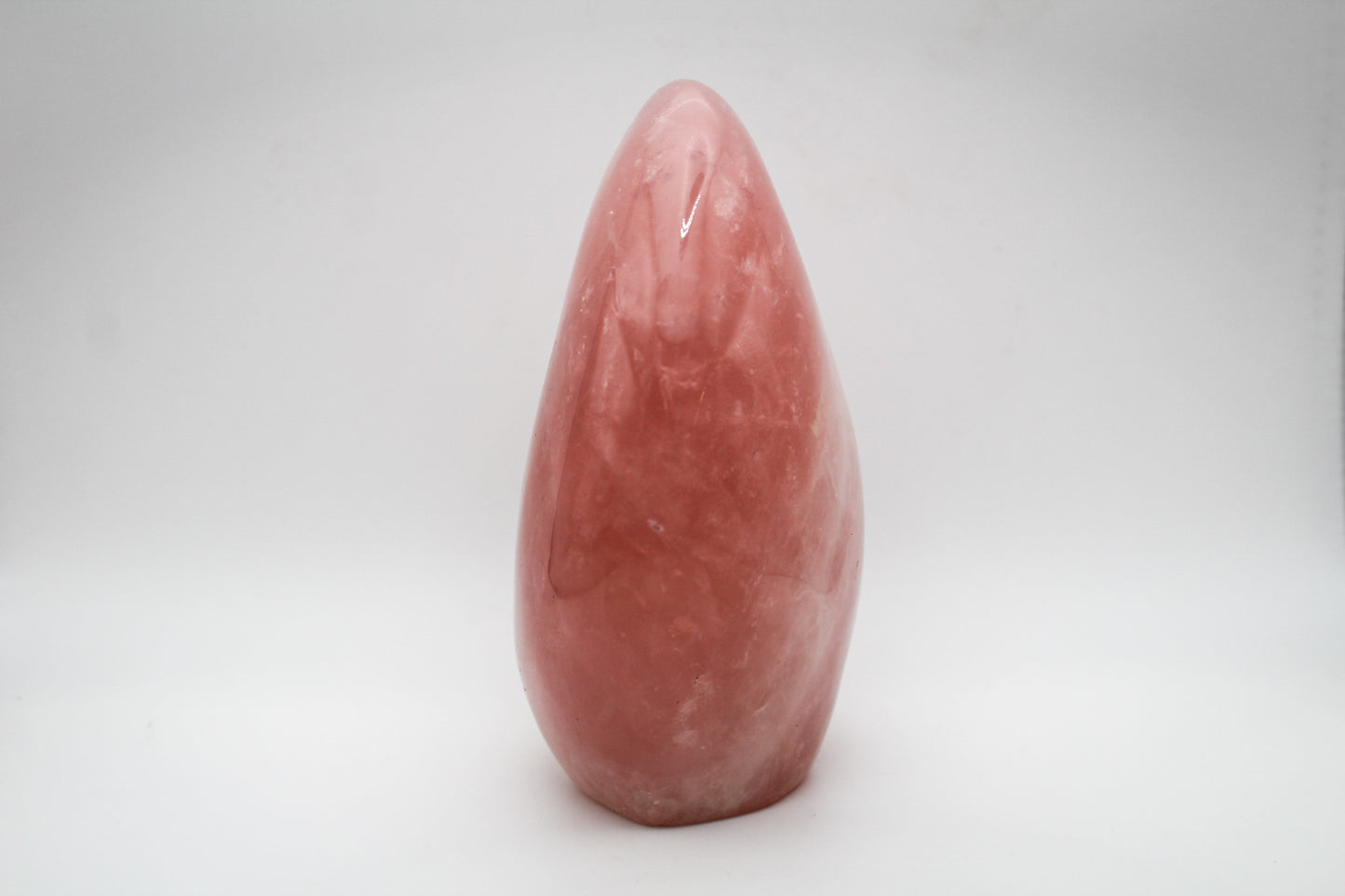 A polished, pink rose quartz crystal free form on a white background.