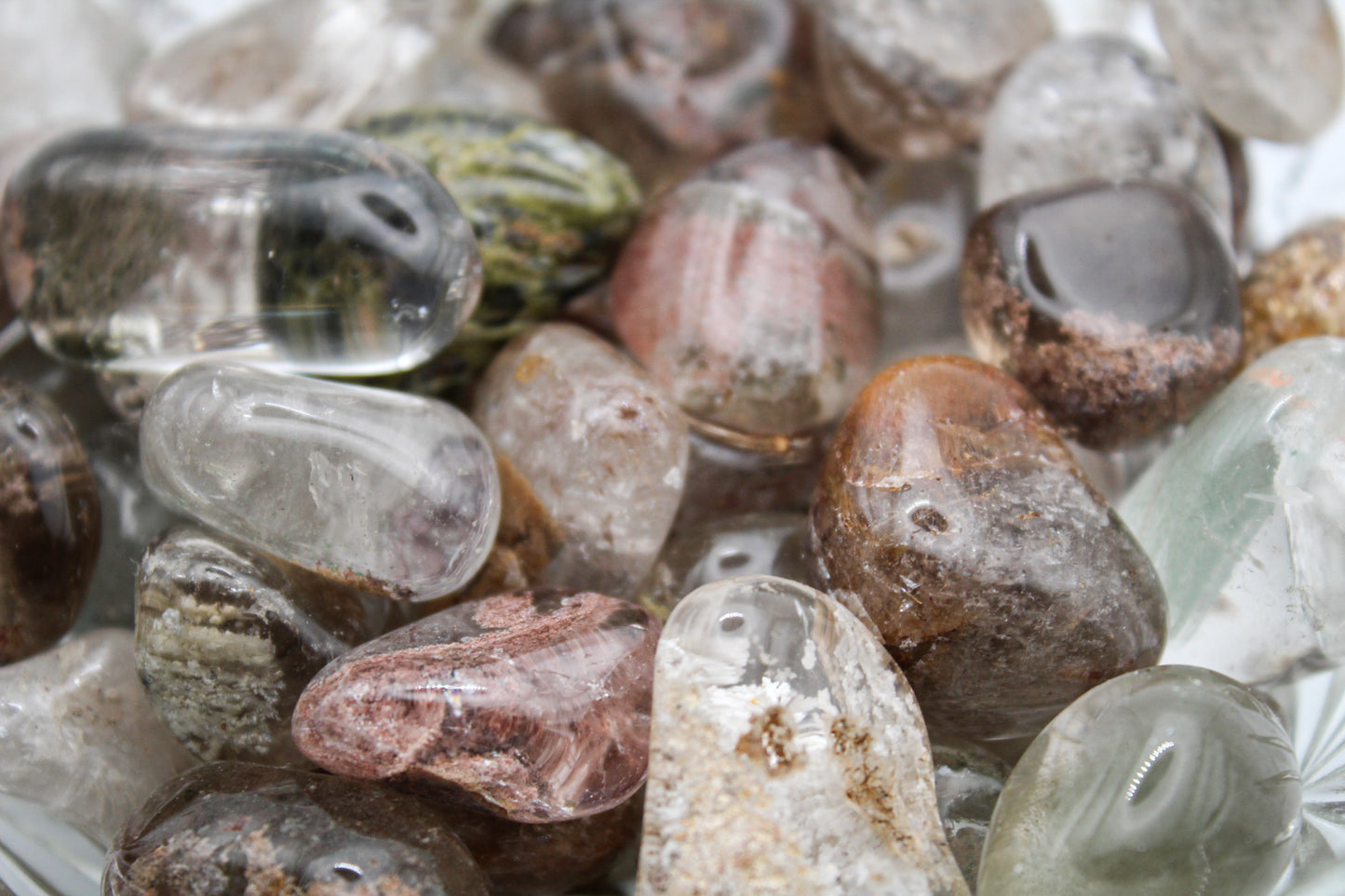 A collection of various polished garden quartz crystals arranged in a bowl.