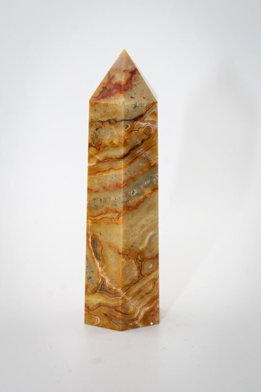 A polished yellow crazy lace agate crystal tower with natural variations in color and pattern.