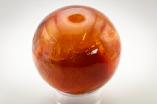 A polished carnelian stone sphere, typically used for decoration or as a crystal in healing practices.