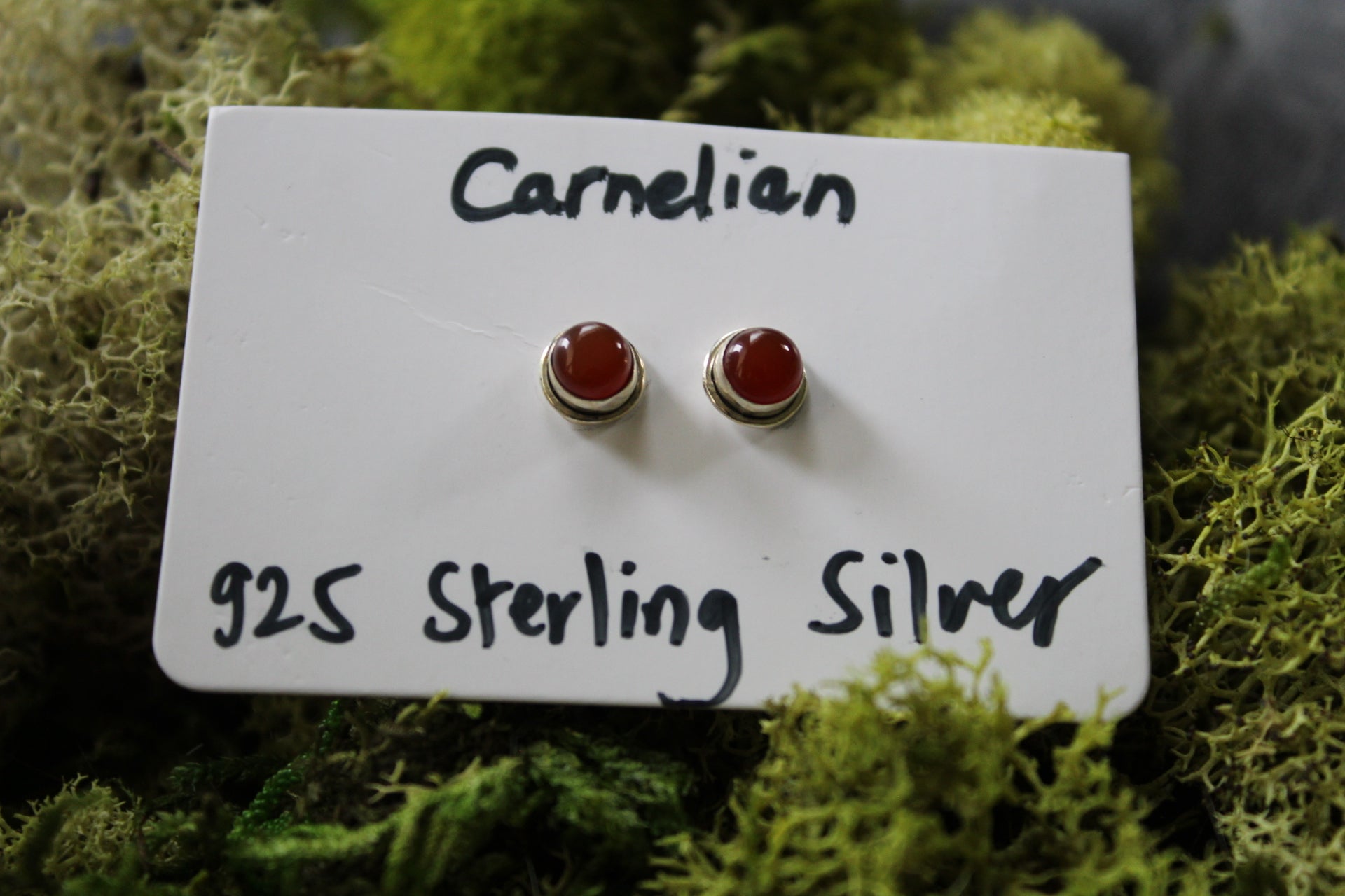 A pair of carnelian stone stud earrings with silver metallic caps.