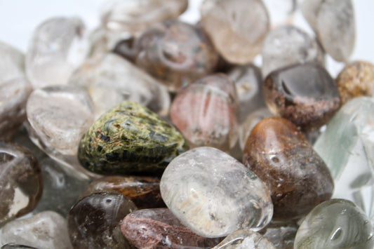 A collection of various polished garden quartz crystals arranged in a bowl.