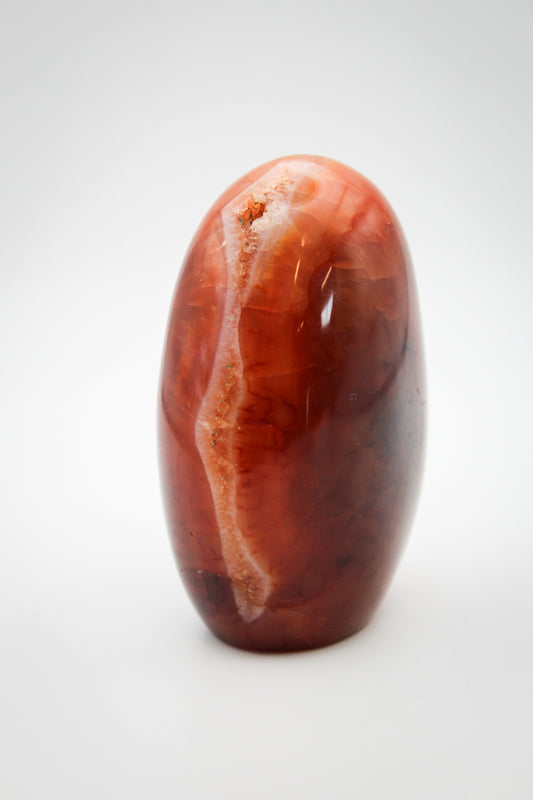 A polished carnelian stone with a free form shape, featuring an orange to red gradient color.