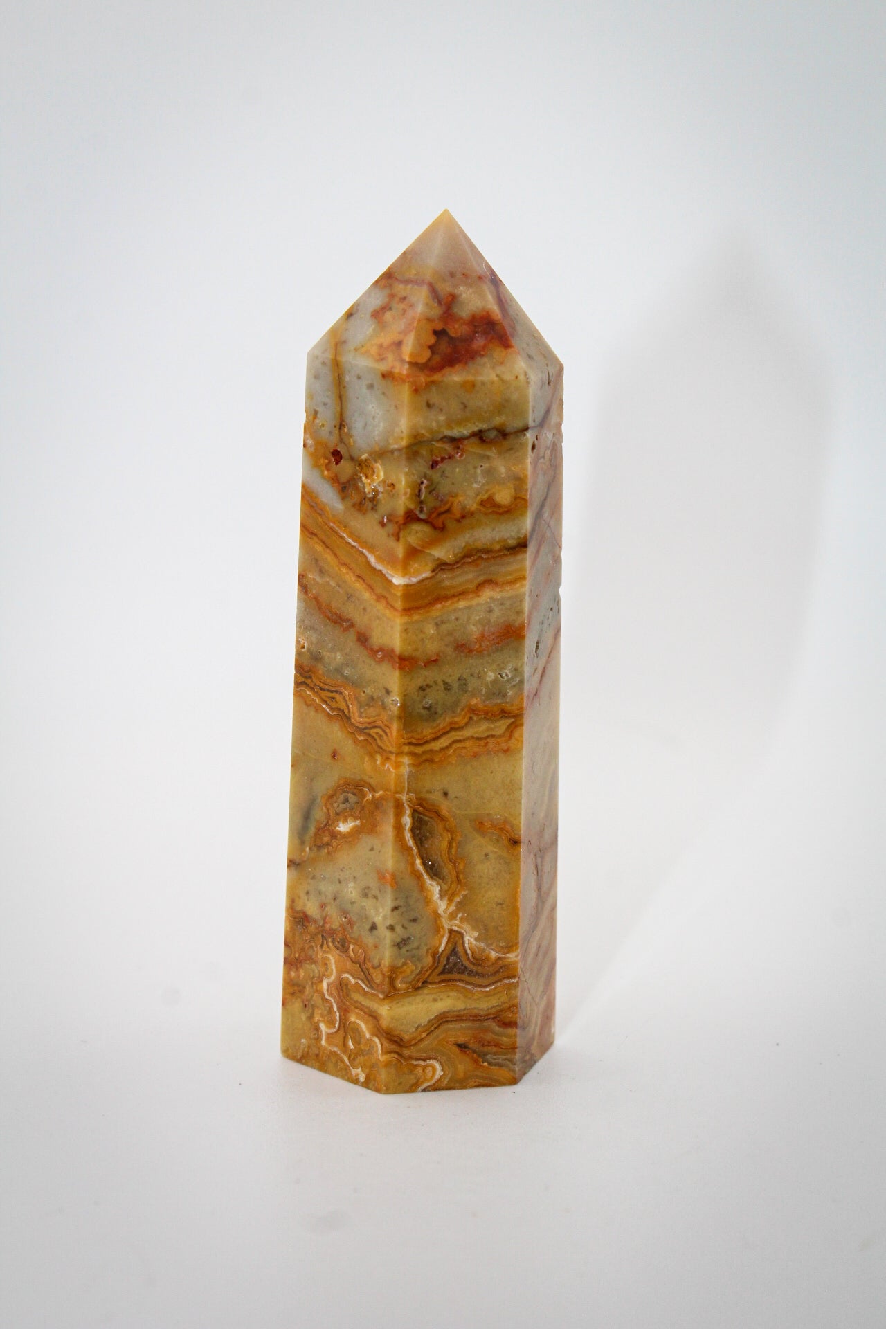A polished yellow crazy lace agate crystal tower with natural variations in color and pattern.