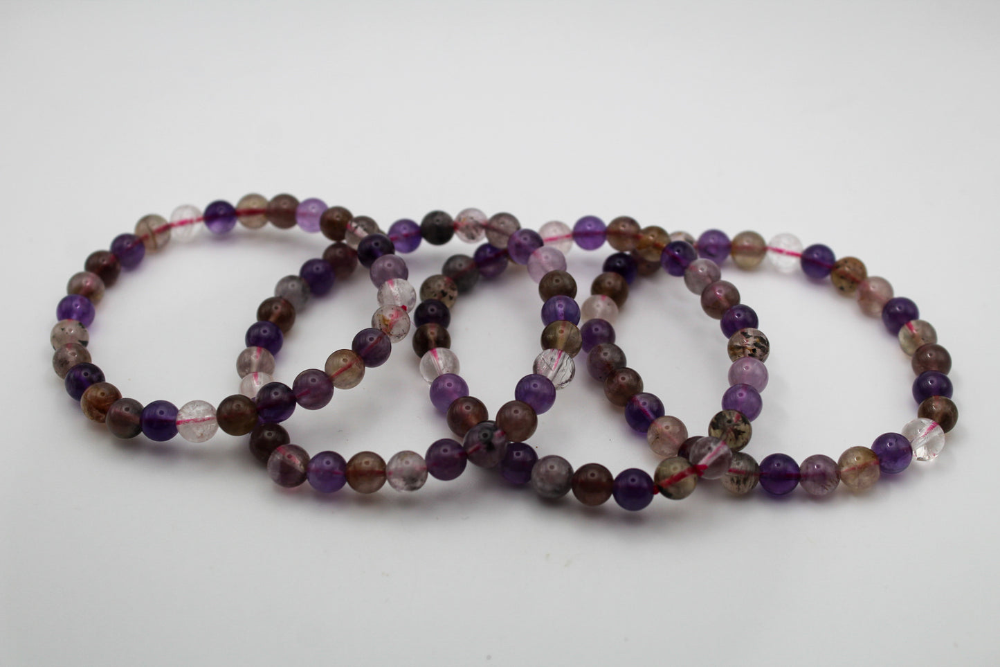 A series of multicolored beaded bracelets stacked together, featuring various shades of purple, brown, and clear.