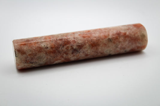 A polished sunstone harmonizing rod with a red and white color pattern, used for decoration.