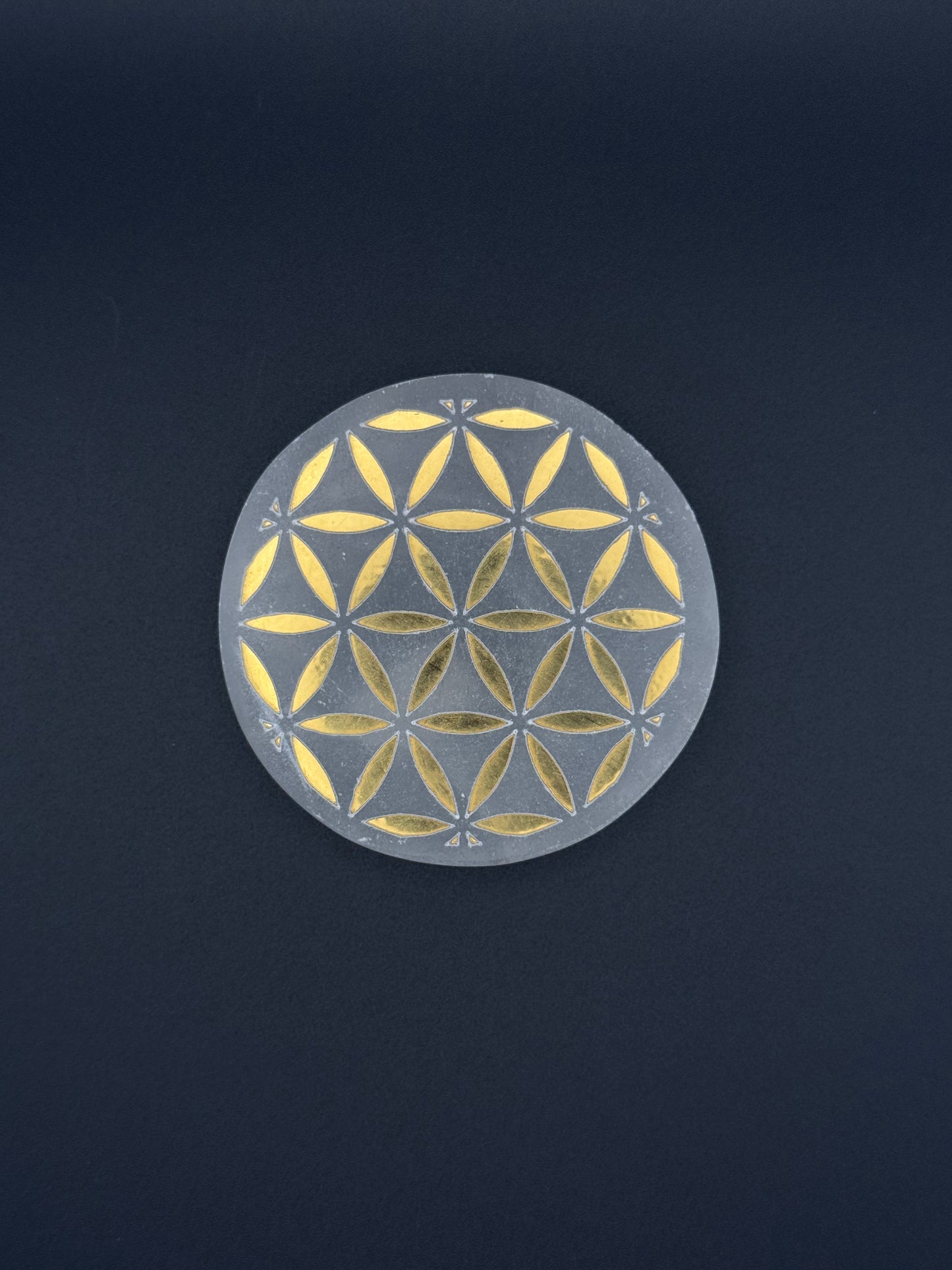 Selenite coaster with engraved flower of life symbol in gold.