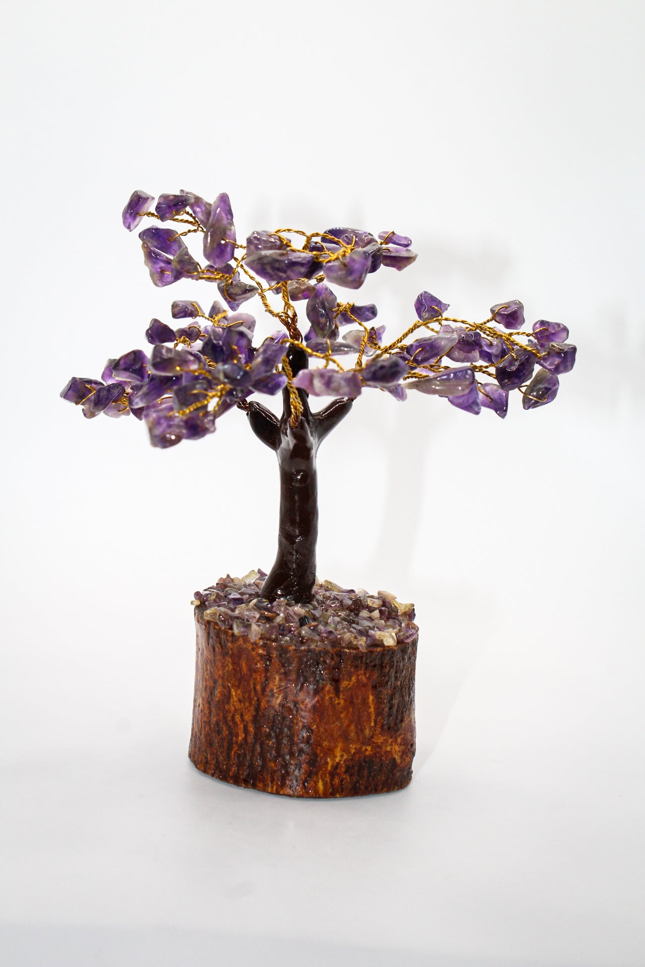 A sculpture of an amethyst crystal tree with gold-colored branches on a wooden base.
