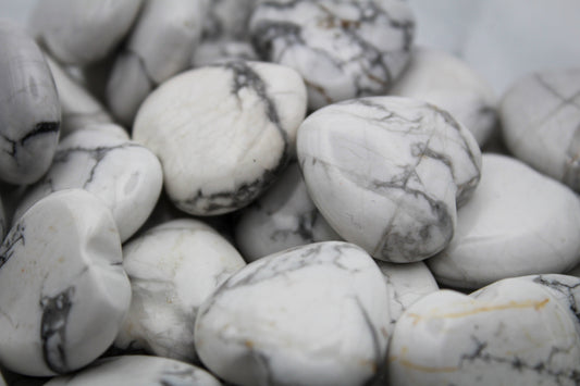 A close-up of several white howlite hearts stones with a marbled pattern.