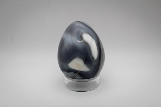 An egg-shaped polished orca agate stone.