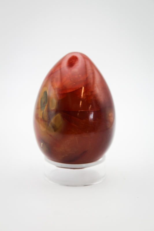 A polished carnelian egg-shaped stone on a clear stand.