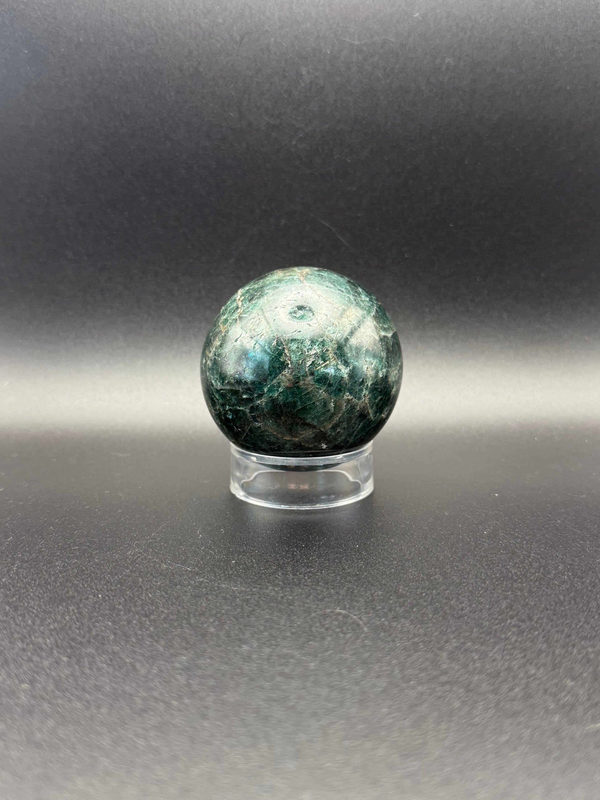 Polished green apatite crystal in the shape of a sphere.
