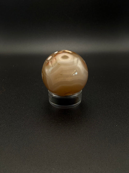 Flower agate polished crystal in the shape of a sphere.