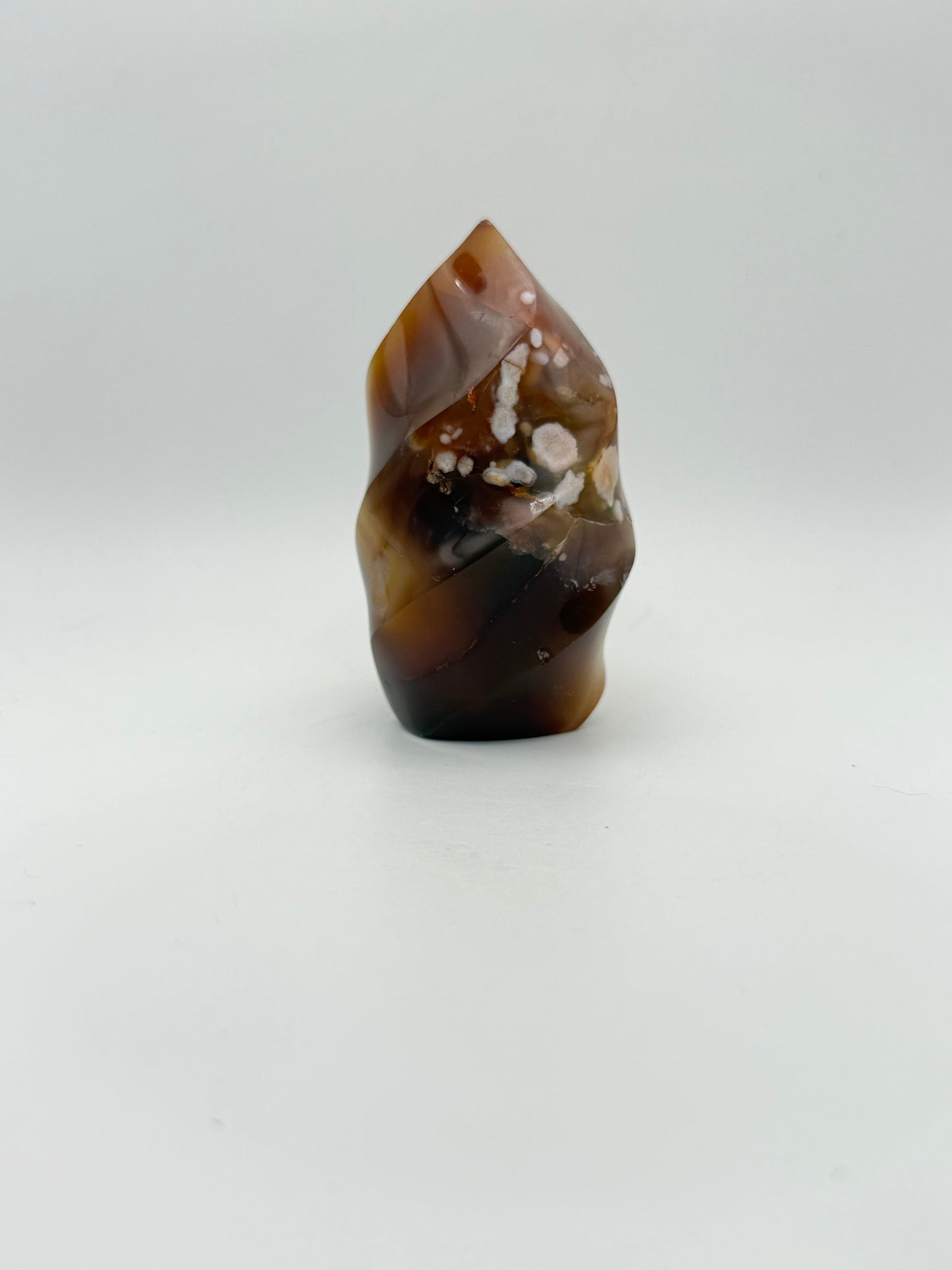 A polished carnelian stone with a flame shape, featuring an orange to red gradient color.
