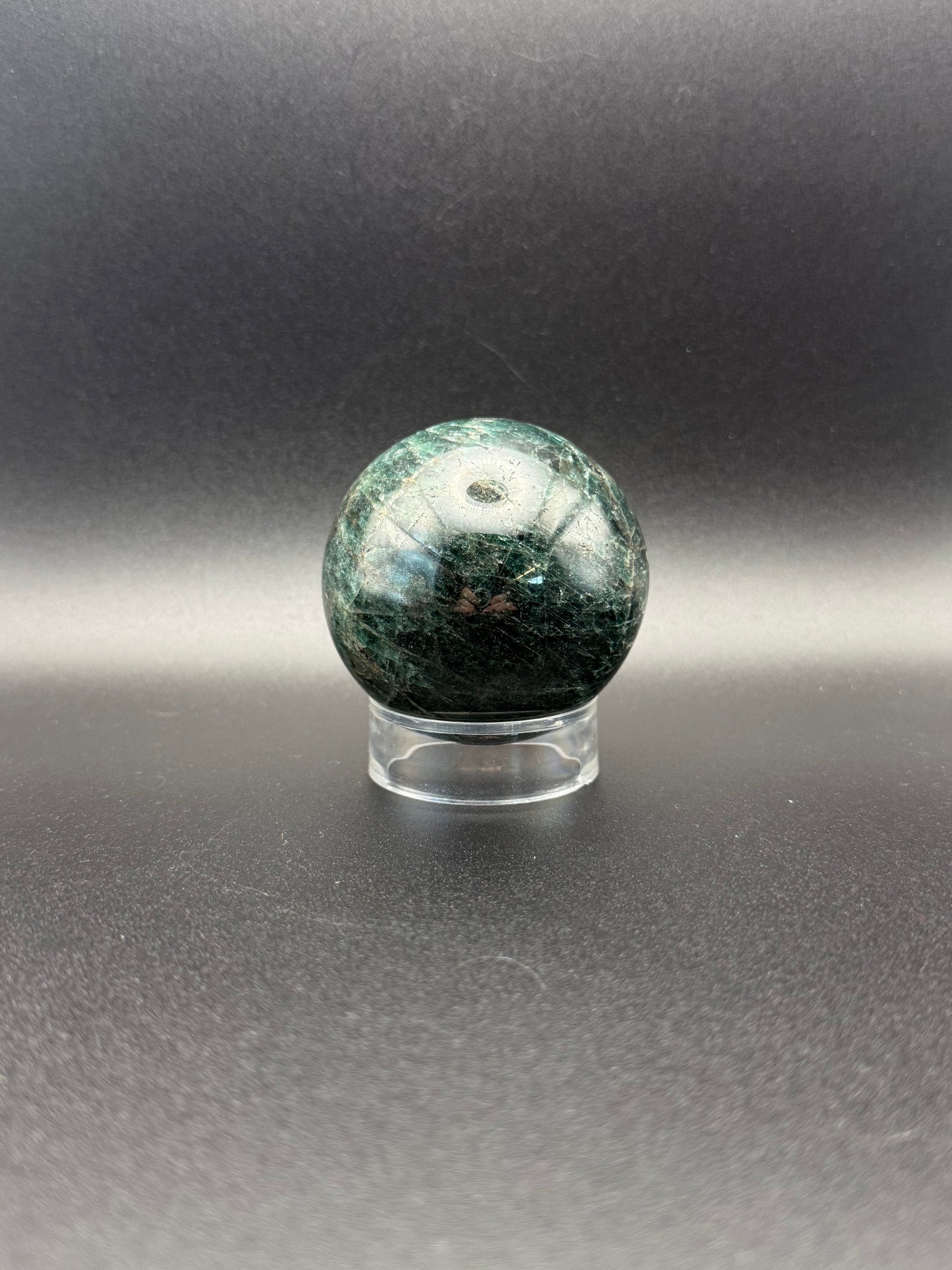 Polished green apatite crystal in the shape of a sphere.